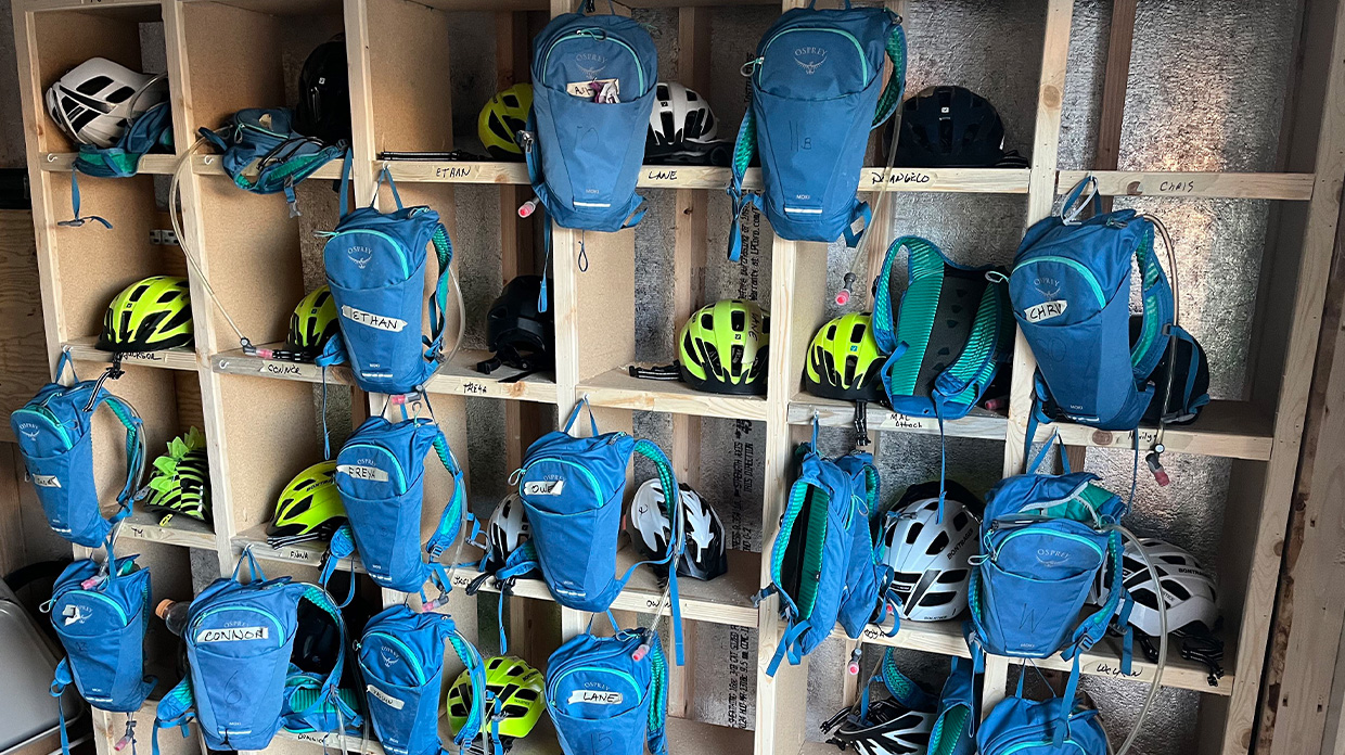 Wooden storage cubbies filled with bike helmets and water hydration backpacks